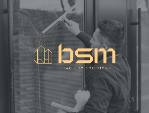 A person cleaning a glass window with a squeegee; the text "bsm Facility Solutions" and a geometric logo are overlaid in yellow on the image.